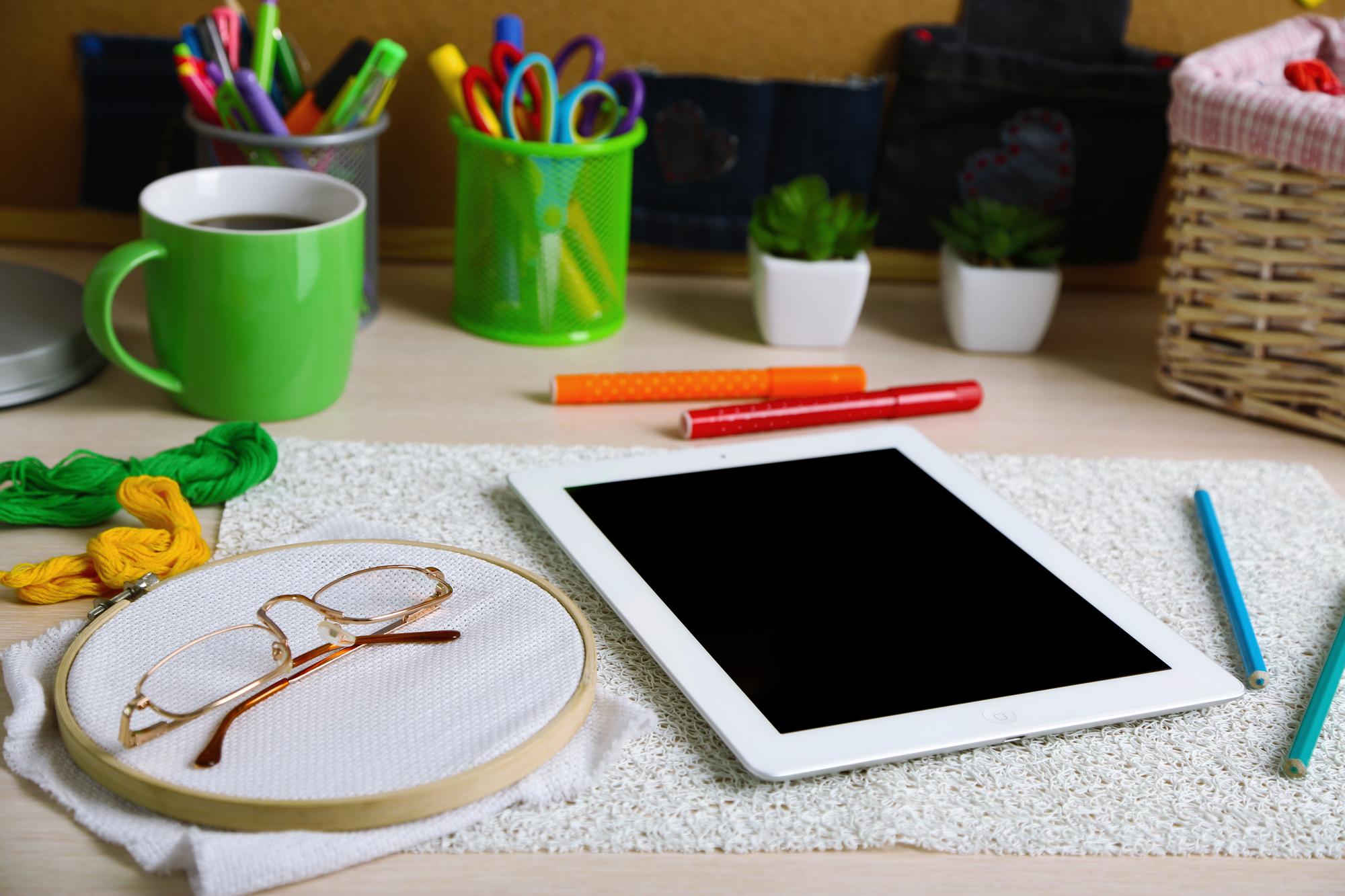 Studio desk with threads and digitized embroidery file on tablet